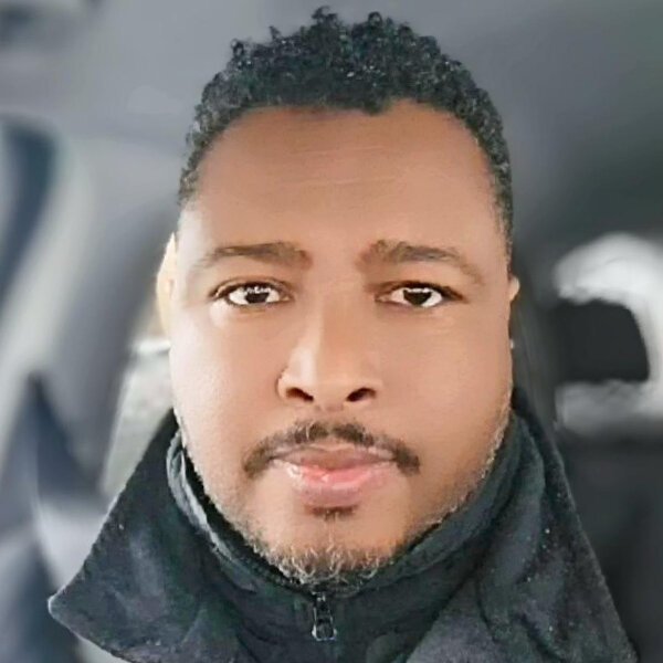 Islamic Center A man with a beard and glasses wearing a light blue garment and collared shirt stands against a white background. Islam